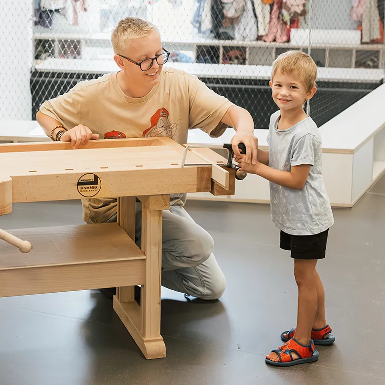 Erzieher im Kindergarten mit Kind an der Werkbank